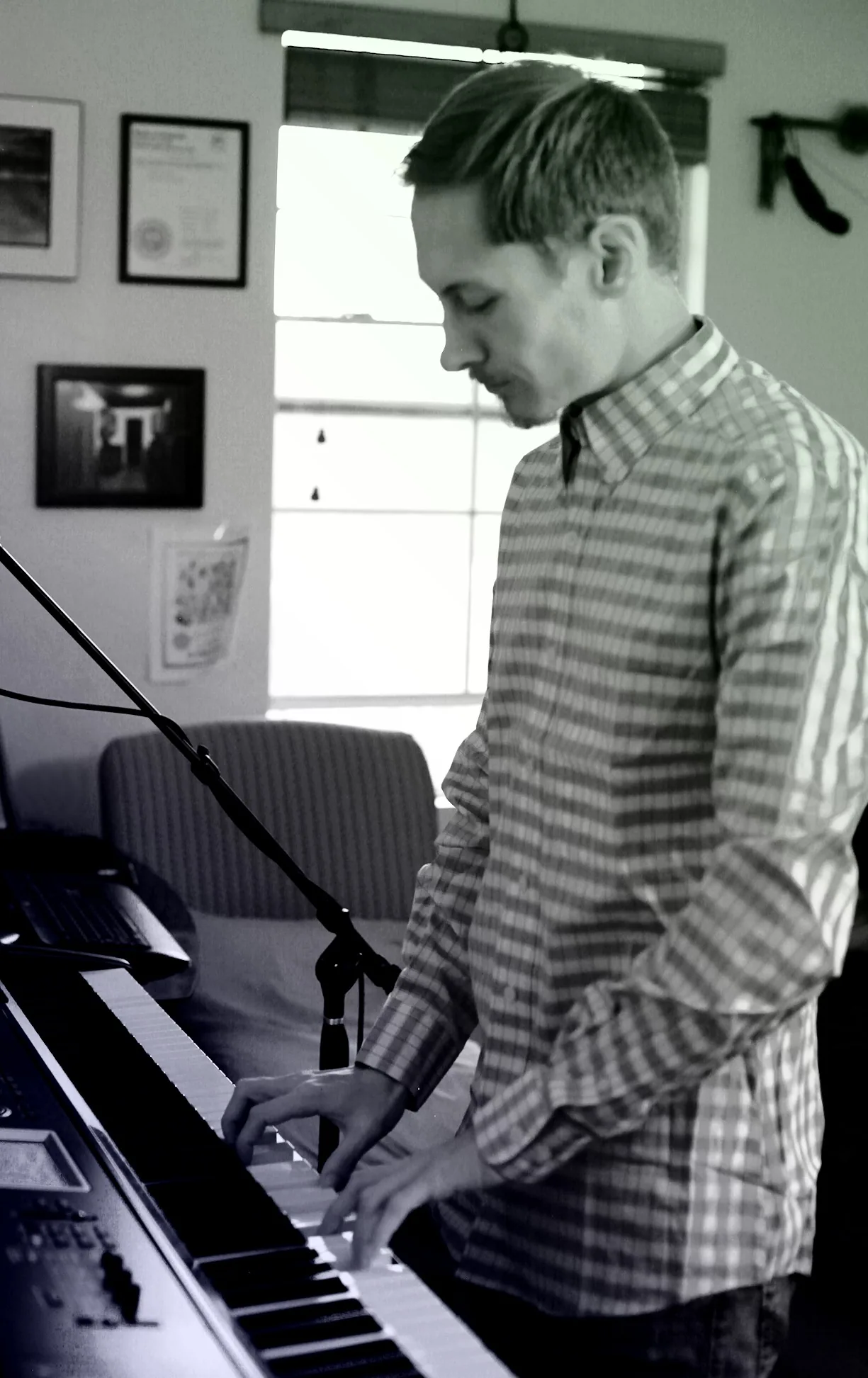 Vertical black-and-white portrait of Ryan performing on a keyboard